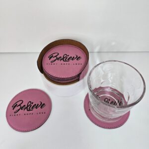 Pink coasters with "Believe" text and glass.