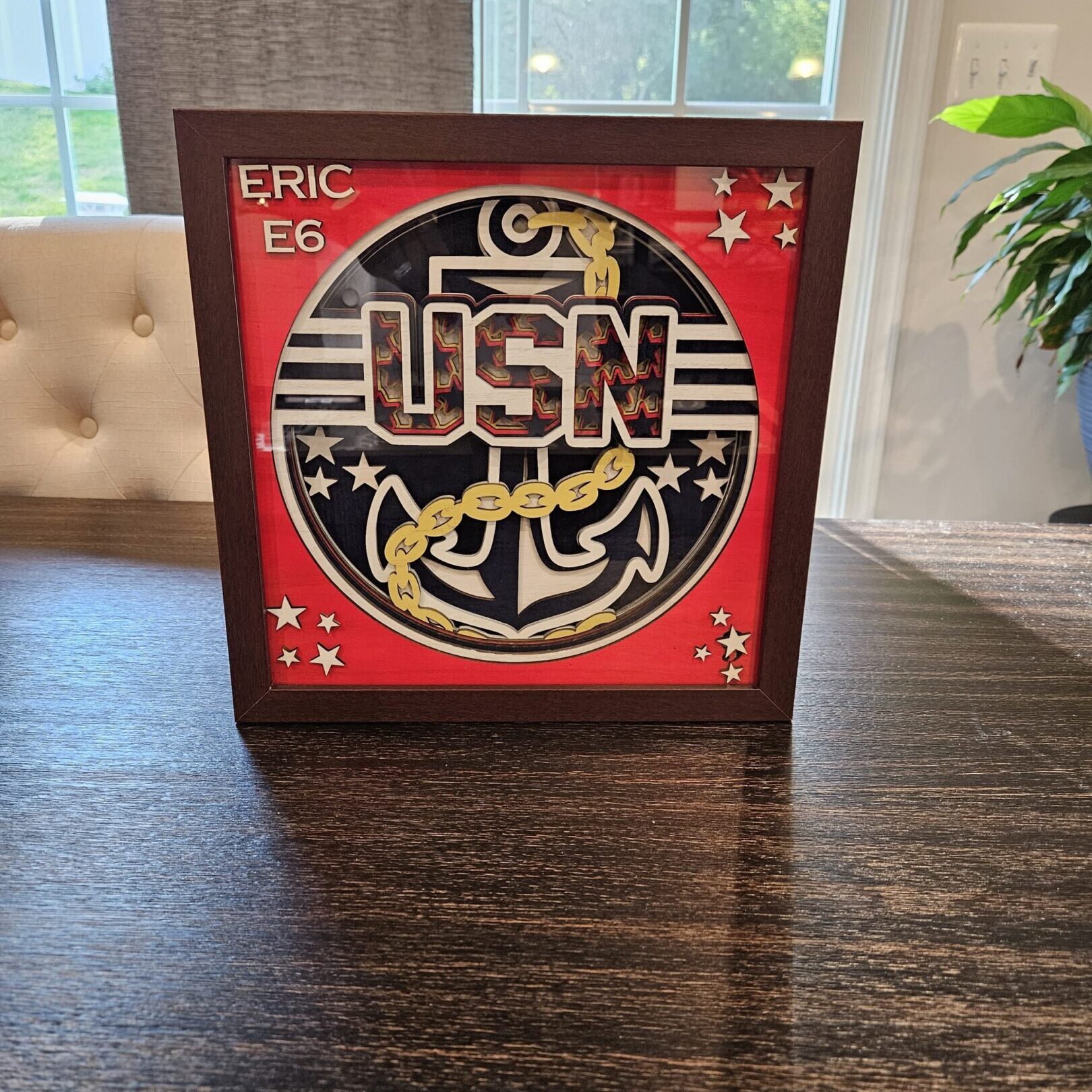 Framed USN insignia on wooden table.