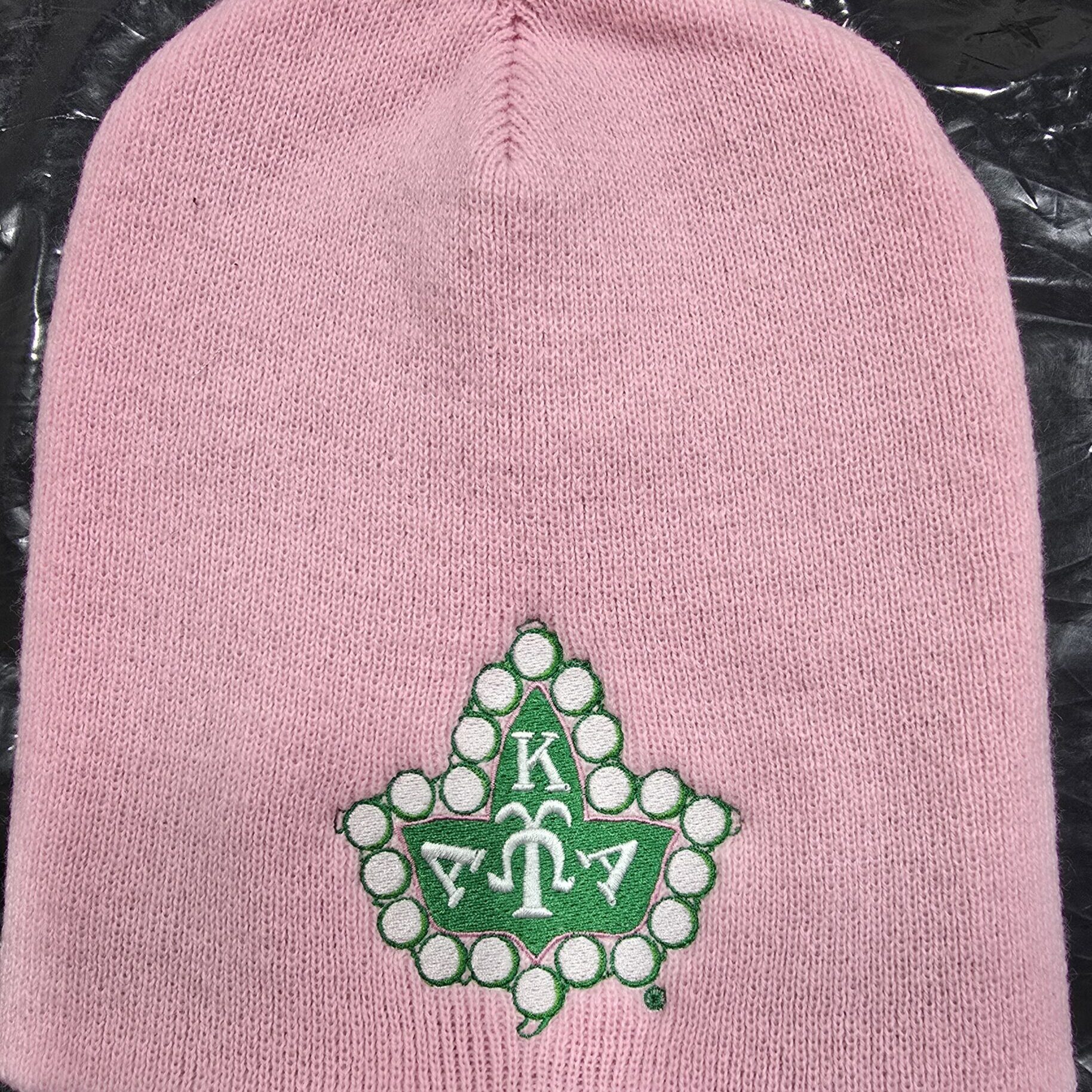Pink knit beanie with green embroidered maple emblem